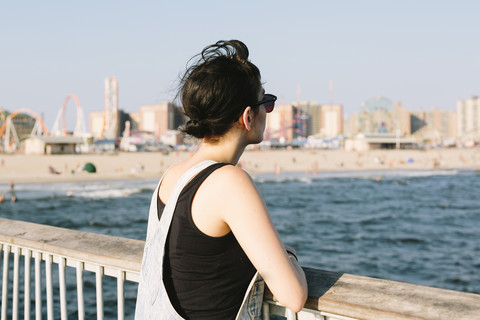 USA, New York, Coney Island, junge Frau entspannt sich auf dem Steg, lizenzfreies Stockfoto