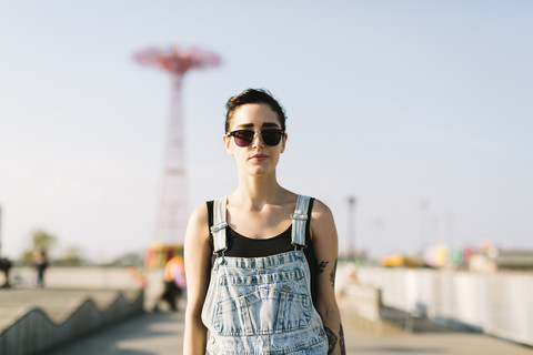 USA, New York, Coney Island, junge Frau mit Fahrgeschäft im Hintergrund, lizenzfreies Stockfoto