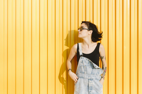 Junge Frau steht vor einer gelben Wand, lizenzfreies Stockfoto