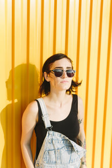 Young woman standing against a yellow wall - GIOF000657