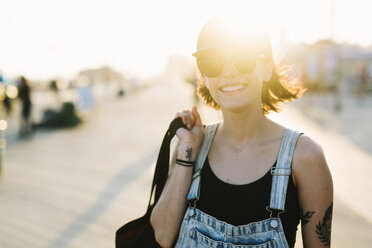 USA, New York, Coney Island, lächelnde junge Frau auf der Strandpromenade bei Sonnenuntergang - GIOF000658