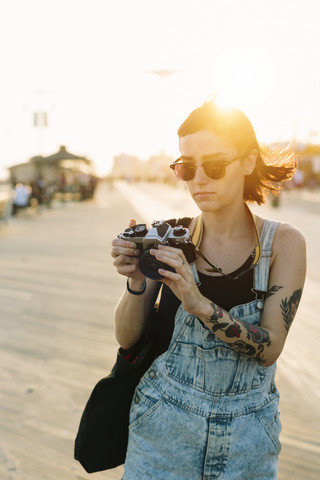 USA, New York, Coney Island, junge Frau schaut bei Sonnenuntergang in die Kamera, lizenzfreies Stockfoto