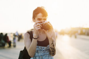 USA, New York, Coney Island, young woman taking photos at sunset - GIOF000665