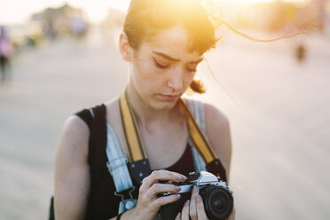 USA, New York, Coney Island, junge Frau schaut bei Sonnenuntergang in die Kamera - GIOF000667