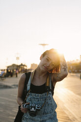 USA, New York, Coney Island, junge Frau mit Kamera bei Sonnenuntergang - GIOF000670