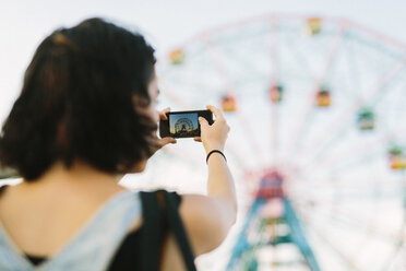 USA, New York, Coney Island, young woman taking a cell phone picture at the amusement park - GIOF000677