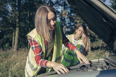 Zwei junge Frauen mit Sicherheitswesten am beschädigten Auto - DAPF000013