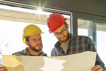 Zwei Handwerker betrachten einen Bauplan auf einer Baustelle - LAF001591