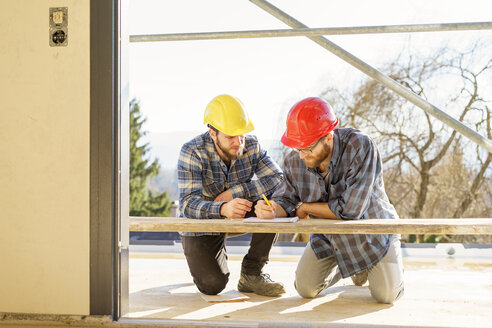 Zwei Handwerker, die auf einer Baustelle diskutieren und Notizen machen - LAF001592