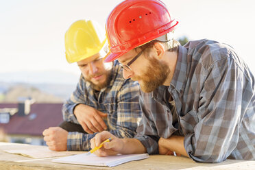 Zwei Handwerker, die auf einer Baustelle diskutieren und Notizen machen - LAF001593
