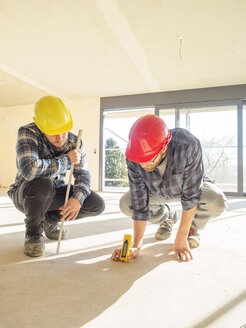 Two craftsmen with measuring device in construction site - LAF001598