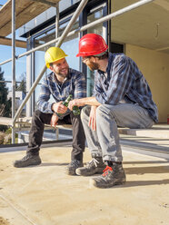 Zwei Handwerker stoßen auf einer Baustelle mit Bierflaschen an - LAF001599