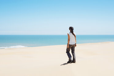 Namibia, Namib desert, Swakopmund, woman walking among the dunes of the desert to the sea - GEMF000630