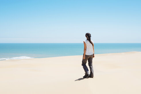 Namibia, Namib-Wüste, Swakopmund, Frau geht zwischen den Dünen der Wüste zum Meer - GEMF000630