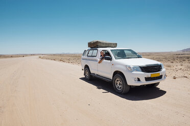 Namibia, Namib-Wüste, Swakopmund, Mann auf einem 4x4 Auto mit Zelt auf dem Dach in einer staubigen Straße - GEMF000632