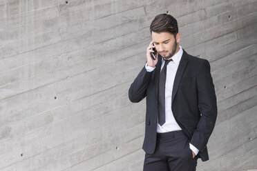 Geschäftsmann im schwarzen Anzug telefoniert mit Smartphone - SIPF000072
