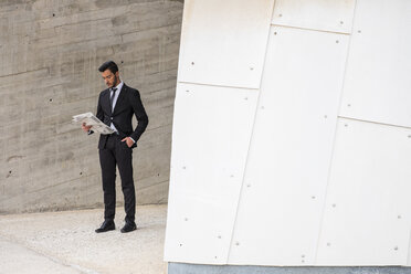 Businessman wearing black suit reading newspaper - SIPF000082