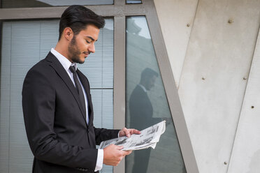 Businessman wearing black suit reading newspaper - SIPF000084