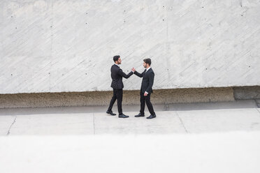 Two businessmen wearing black suits greeting each other - SIPF000087