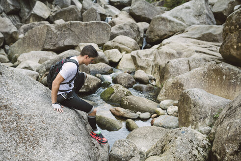 Spanien, A Capela, Ultra-Trail-Läufer klettert auf einen Felsen - RAEF000783