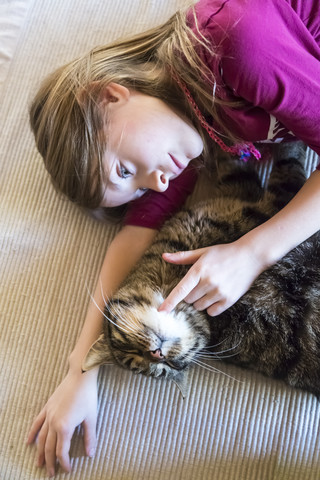 Mädchen streichelt getigerte Katze, lizenzfreies Stockfoto