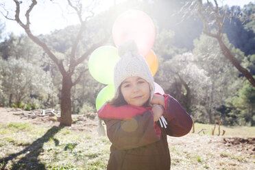Spain, Gallifa, portrait of little girl with balloons wearing bobble hat - VABF000062