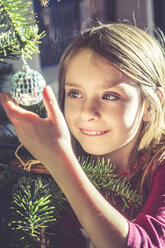 Portrait of smiling girl decorating Christmas tree - SARF002463