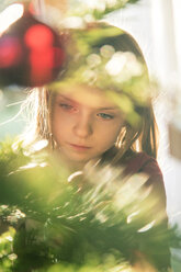 Porträt eines Mädchens beim Schmücken des Weihnachtsbaums - SARF002466