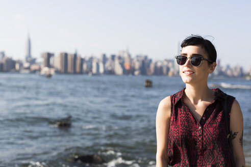 USA, New York City, Porträt einer lächelnden jungen Frau mit Sonnenbrille - GIOF000682