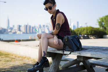 USA, New York City, Brooklyn, tattooed young woman sitting on a bench - GIOF000688