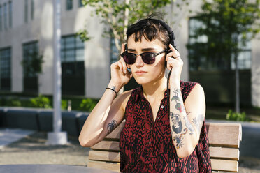 USA, New York City, Williamsburg, Porträt einer tätowierten jungen Frau mit Kopfhörern - GIOF000703