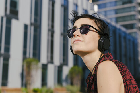 Porträt einer jungen Frau mit Kopfhörern und Sonnenbrille - GIOF000707