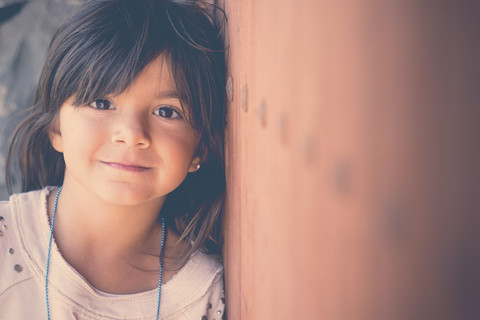 Portrait of smiling girl leaning against wall stock photo