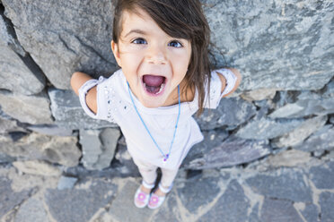 Portrait of little girl with mouth open in front of a rock face - SIPF000106
