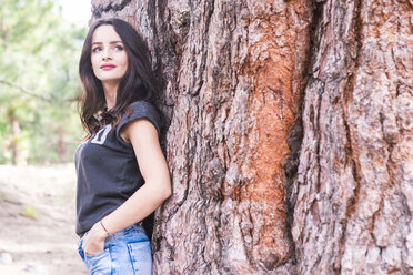 Spain, Tenerife, portrait of woman leaning against tree trunk - SIPF000107