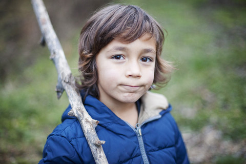 Porträt eines kleinen Jungen mit einem Zweig in der Natur, lizenzfreies Stockfoto
