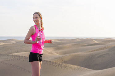 Junge Frau, die am Strand joggt und eine Pause macht - DIGF000005