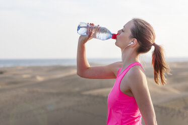 Junge Frau, die am Strand joggt und eine Pause macht - DIGF000006