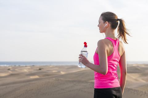 Junge Frau, die am Strand joggt und eine Pause macht, lizenzfreies Stockfoto