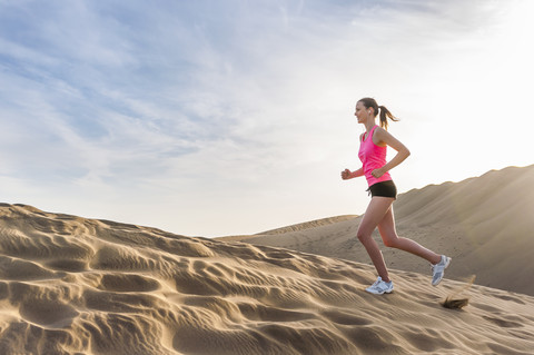 Junge Frau joggt am Strand, lizenzfreies Stockfoto