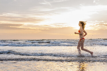 Woman wearing bikini jogging at the sea - DIGF000011