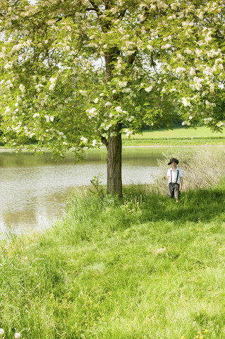 Italien, kleiner Junge in alter Kleidung unter einem Baum stehend, lizenzfreies Stockfoto