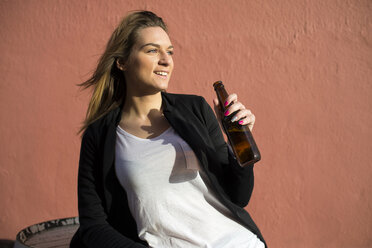 Portrait of relaxed woman holding bottle of beer - KIJF000111