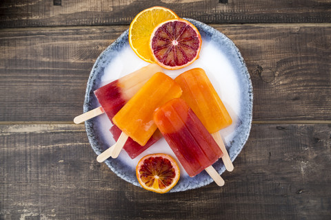 Plate of different homemade orange ice lollies and orange slices stock photo