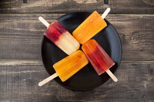 Plate of four different homemade orange ice lollies - SARF002481
