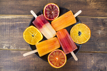 Plate of four different homemade orange ice lollies and four orange slices - SARF002482