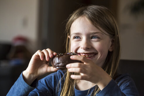 Porträt eines lächelnden Mädchens, das einen Schokoladenkrapfen isst - SARF002486
