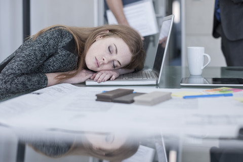Frau schläft auf einem Tisch im Büro, lizenzfreies Stockfoto
