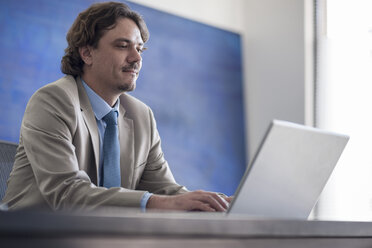 Businessman at desk using laptop - ZEF007989