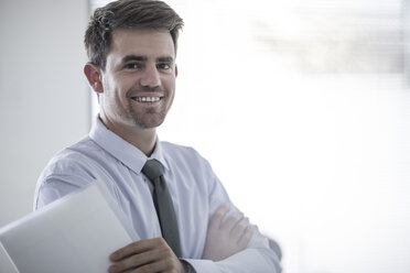 Portrait of smiling businessman holding papers - ZEF008007